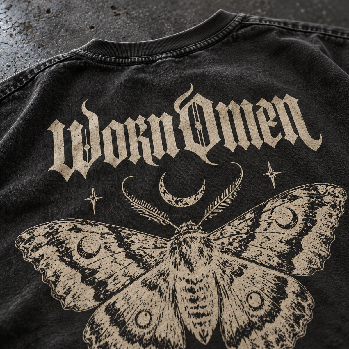 Close-up of Nocturne's gothic wordmark and moth print on washed-black cotton