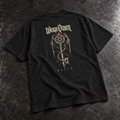 WORN OMEN Relic solid-black oversized tee with ornate key artwork on the back, laid on weathered steel